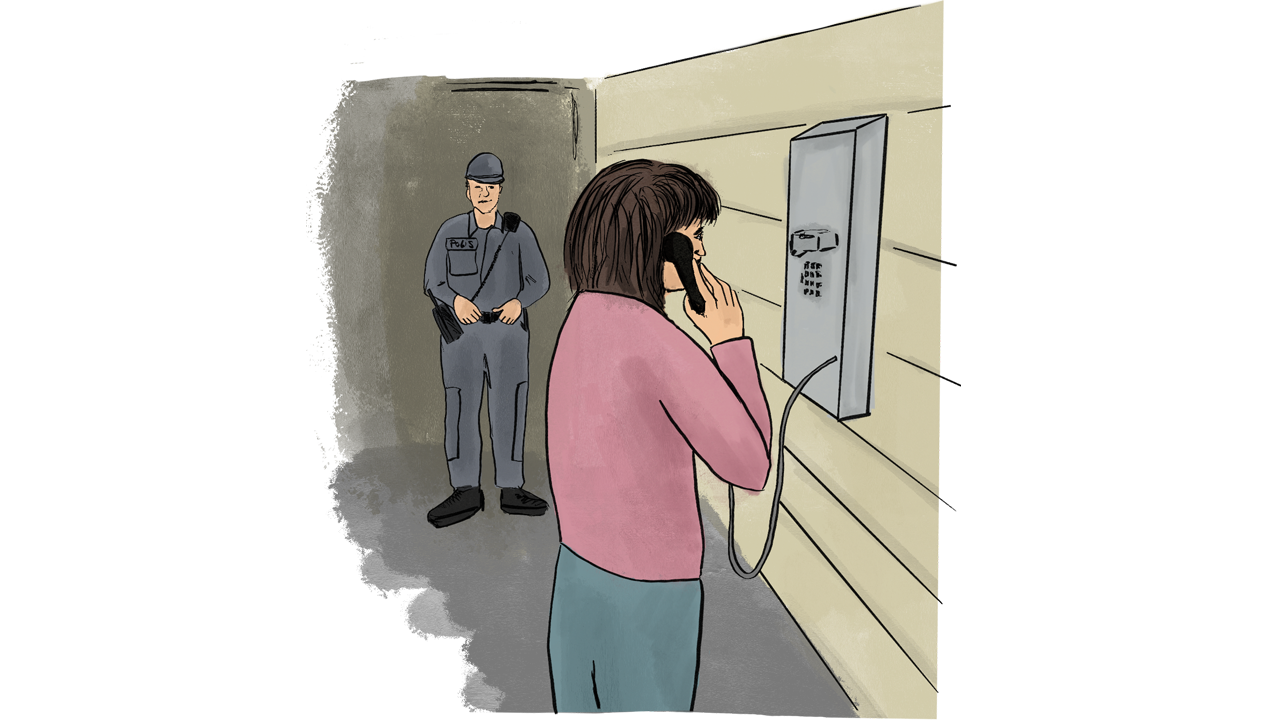 A female inmate on the phone while a guard watches